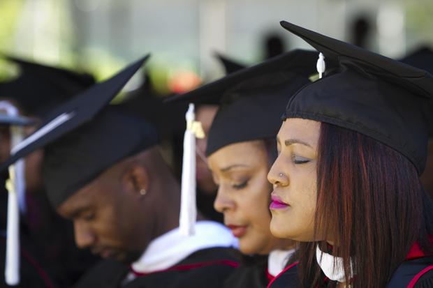 CSUN graduates receiving their master's degree bow their heads for a prayer during the Black graduation ceremony held at the lawn behind Manzanita Hall, Sunday. Charlie Kaijo/Senior Staff