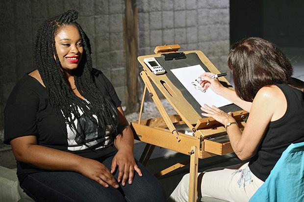 Amber Bernardez, 25, an apparel design and merchandising major, poses for a caricature artist to finish her drawing. Photo Credit: Lucas Esposito / Daily Sundial