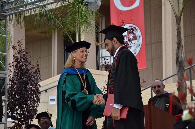 A graduate from the David Nazarian College of Business and Economics is congratulated by President Dianne Harrison during commencement ceremonies at the Oviatt Lawn Thursday morning. Photo Credit: Vincent Nguyen / Contributor