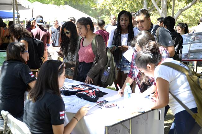 Students gather at the booth for Unified We Serve during the Meet the Clubs event on Tuesday, Sept. 2, 2014 on Bayramian lawn. Newly university recognized clubs at CSUN include faith-based clubs, a Latina culture/academic promotion club, and a worldwide awareness to health disparities club. Photo Credit: Alex Vejar/ The Sundial.
