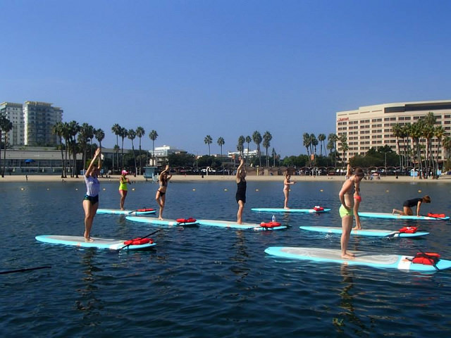 Students try to balance on paddle boards during yoga class in the Marina. Photo courtesy of Yogaaqua.