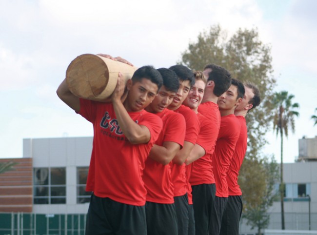 Nic Alegrado leads his squad in lifting a 280 pound log as part of their Navy SEAL training. (Leni Maiai / The Sundial)