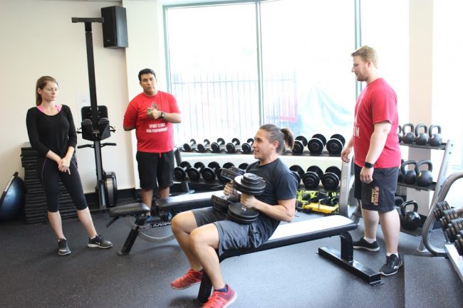 CSUN Rugby fly-half Jordan Rhoades lifting weights as strength and conditioning interns monitor his performance. Photo Credit: Robert Spallone/ The Sundial