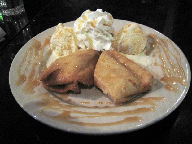 A pastry filled with banana cheesecake, drizzled with caramel sauce, served with a side of whipped cream and two scoops of ice cream. Photo Credit: Michelle Nelson / Staff Reporter