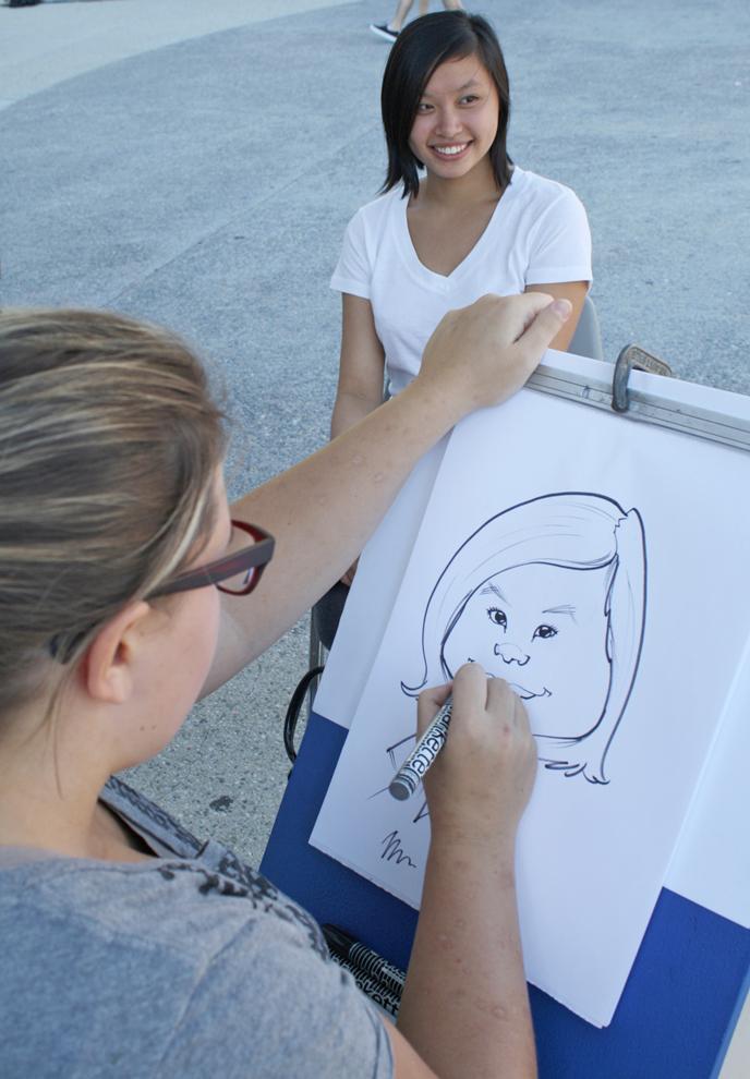 Diana Lin, 21, accounting major sits for Kelcie Gruenberg who has been drawing caricatures for nine years. Students were given the opportunity to be drawn for free during the Hawaiian themed Matafest at the USU on Wednesday. Photo Credit: Mariela Molina / Visual Editor