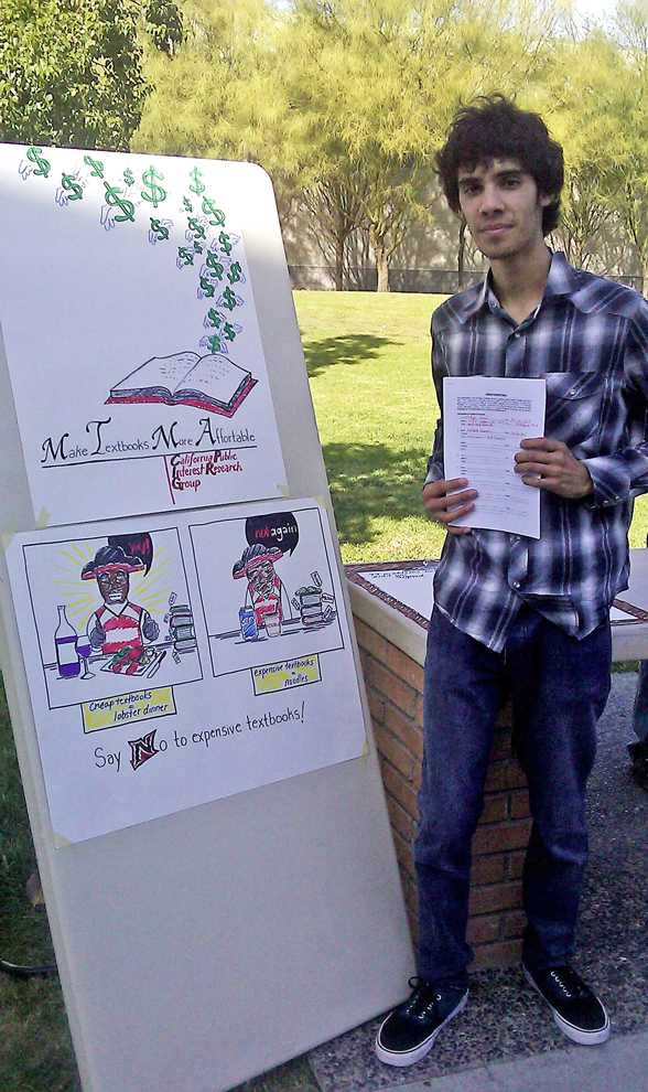 Marcos Castro, CTVA major, stands on Matador Walk holding his petition to bring down college textbook prices. He, along with friends, plans to return throughout November and December to gain signatures for a cause he says students can get behind. Photo Credit: Braulio Campos / Daily Sundial