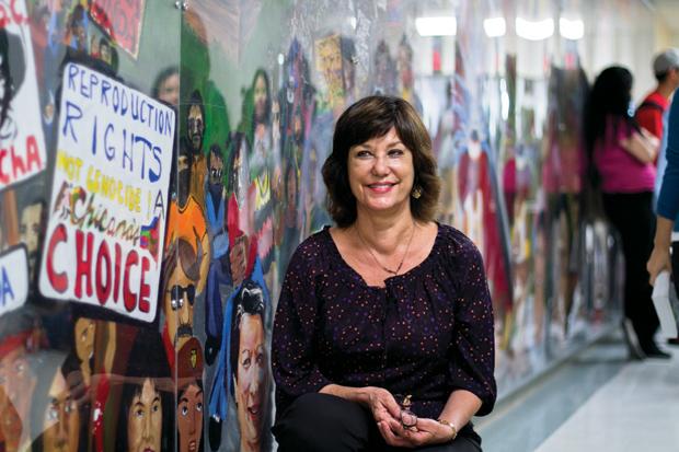 Mary Pardo, department chair of Chicano/a studies, poses next to the mural at Jerome Hall.  Students never knew the Chicano history, arts, or culture, Pardo said. â??They never learned it in high school. Iâ??ve had many students come in and tell me they love that they can learn about it here. Photo credit: Charlie Kaijo / Assistant Photo Editor