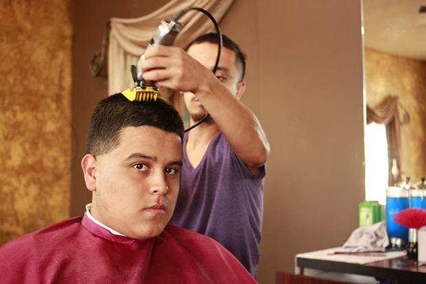 Romo  cuts Richard Lepe's hair at his barber shop. Lepe has been a loyal customer since the shop opened up seven months ago.