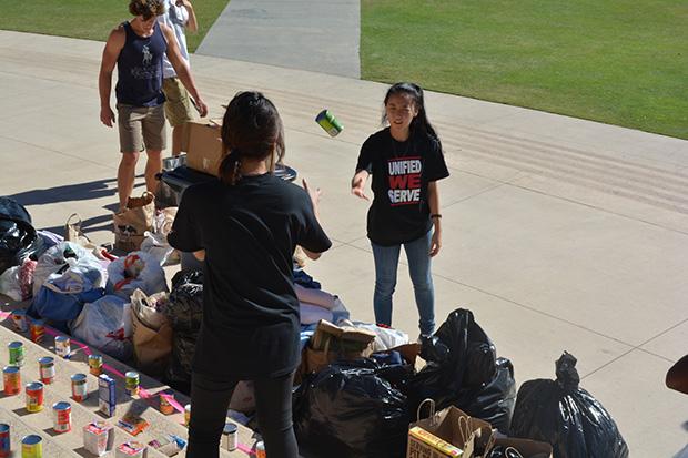 Biology majors, Gloria Yun (Left), 19, and Catherine Han (Right), 19, work diligently to display the items collected during the annual clothing and food drive. Photo credit: John Saringo-Rodriguez / Photo Editor