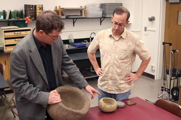Dr. James Snead, director of the Anthropological Research Institute and archeology professor, reveals to Dr. Matthew Des Lauriers, fellow anthropology colleague, a fragment of equipment from the 1928 St. Francis Dam Disaster. Photo Credit: Andrea Alexanian