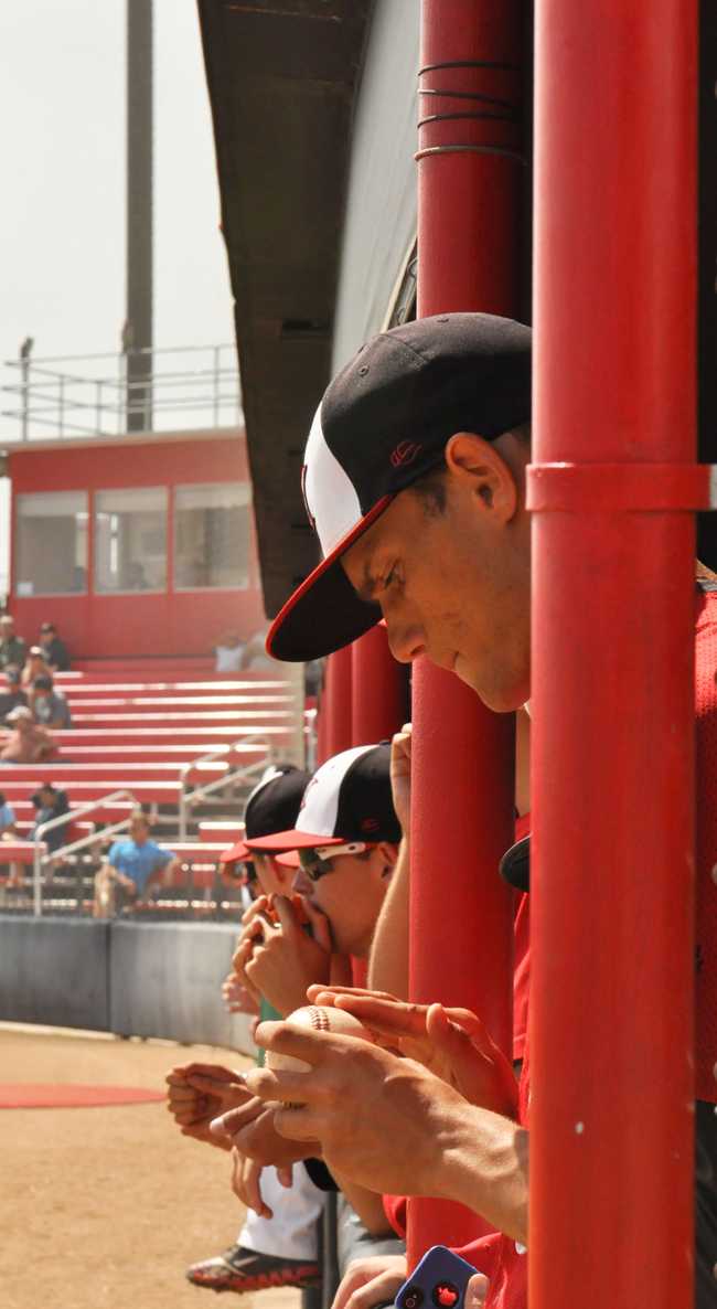 Matadors team mates hang out in the dugout to watch the game while staying in focus as one player rubs the dirt off the ball. Photo Credit: Zuying Chen / Contributor