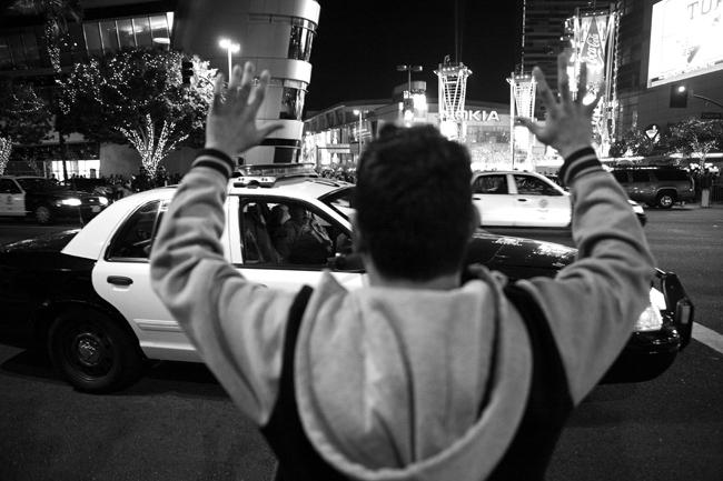 A demonstrator, protesting the shooting death of teenager Mike Brown, holds up his hands chanting, “Hands up, don’t shoot” as the LAPD drives by the Staples Center in downtown LA on Wednesday, Nov. 26, 2014. LAPD officers block the incoming crowd of demonstrators as they try to make their way towards the Staples Center in downtown LA on Wednesday, Nov. 26, 2014. About 130 people were arrested that night for failure to disperse during the protest. Photo Credit: Loren Townsley/Senior Photographer 