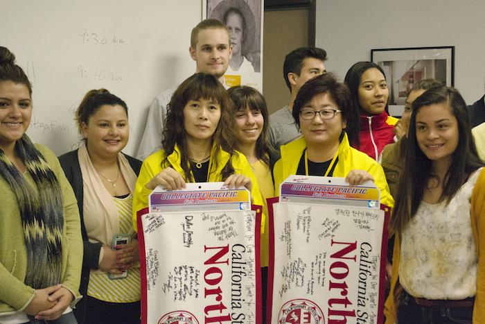 Hye Young Park and Young Mi Hong pose with the banners that were gifted to them by the Journalism students after their presentation. Photo credit: Irene Villalobos