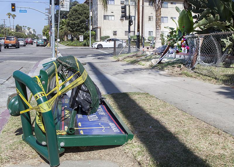 A damaged bus bench at the corner of Lindley Avenue and Roscoe Boulevard on the morning of  Monday June 22, 2015. In the background is the memorial for Desirae Crittenden, 19, a CSUN Student who died at the scene. Photo credit: Matt Rose