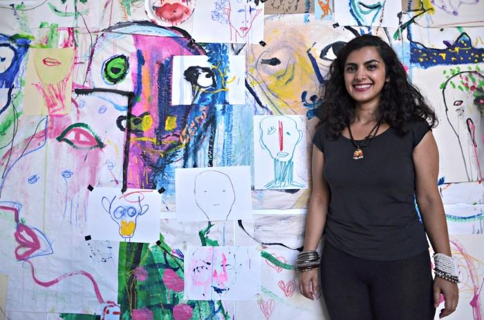 Art student Mehrnoosh Eskandari with her work in the art departments first exhibit of the fall semester. Her untitled work is posted at the Art and Design Center on top of campus. Photo credit: Vincent Nguyen