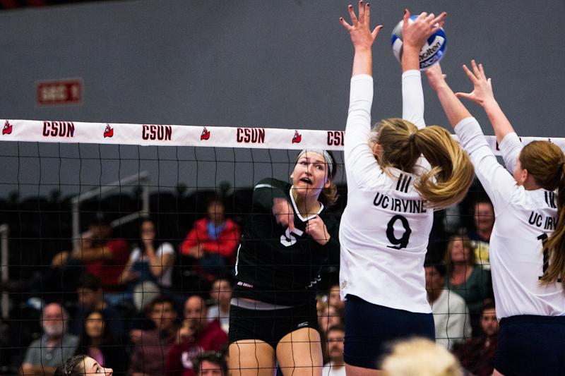 CSUN+volleyball+player+spikes+ball+over+net+which+is+blocked+by+volleyball+players+from+UC+Irvine.