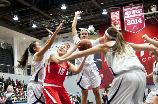 CSUN basketball player struggles to fight through three Master's College Women basketball players.