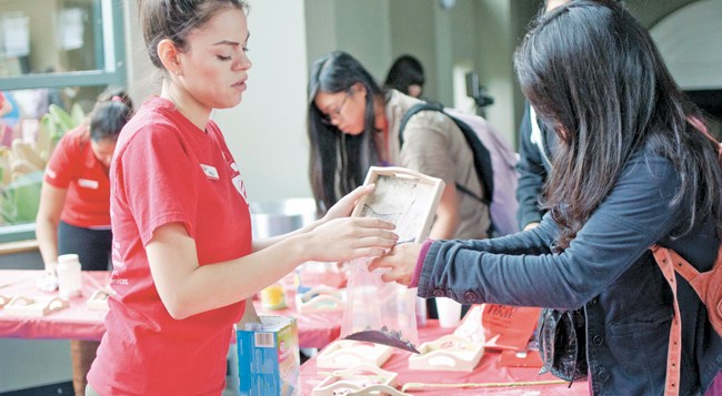 Perla Palacios, 21, Recreation & Tourism Management junior, right, help a student pour sand into the bag at the USU Grand Salon on Tuesday, May 6, 2014 in Northridge, Calif. (File Photo / David Hawkins / The Sundial)