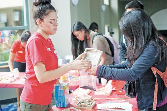Perla Palacios, 21, Recreation & Tourism Management junior, right, help a student pour sand into the bag at the USU Grand Salon on Tuesday, May 6, 2014 in Northridge, Calif. (File Photo / David Hawkins / The Sundial) 