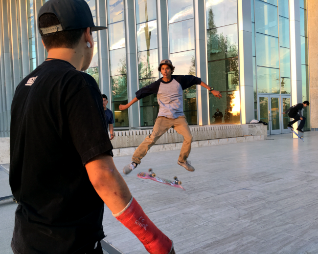 Rick Molina, from Northridge, watches his friend Mauricio Arana, from Granada Hills, perform a hardflip in front of the VPAC Wednesday evening. (Patricia Perdomo / The Sundial)