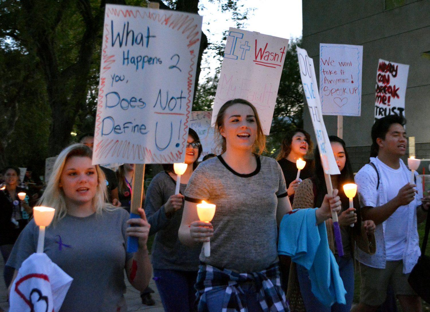 Crowd of men and women carry candles and picket signs