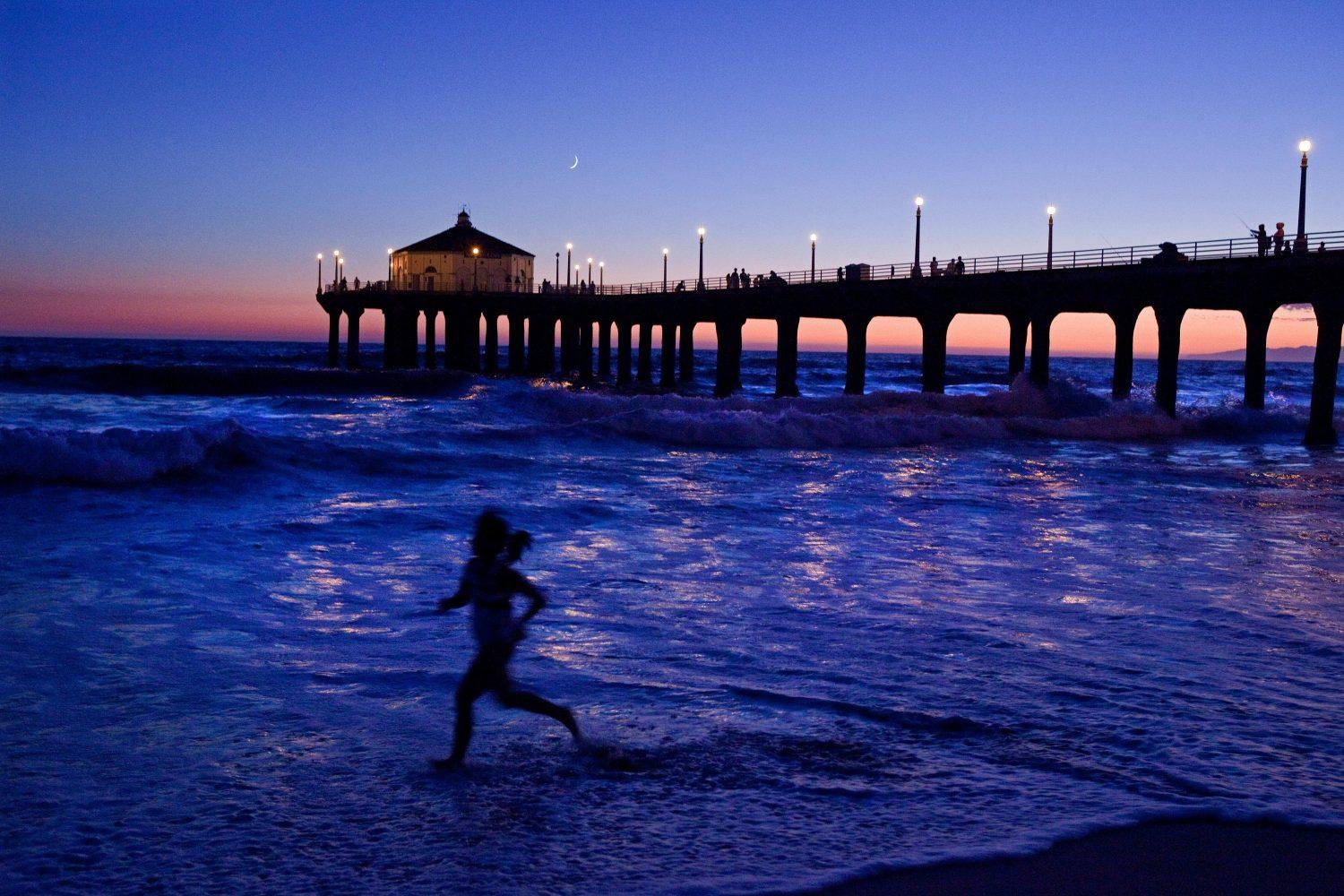 Photo of the ocean at sunset with child running in water