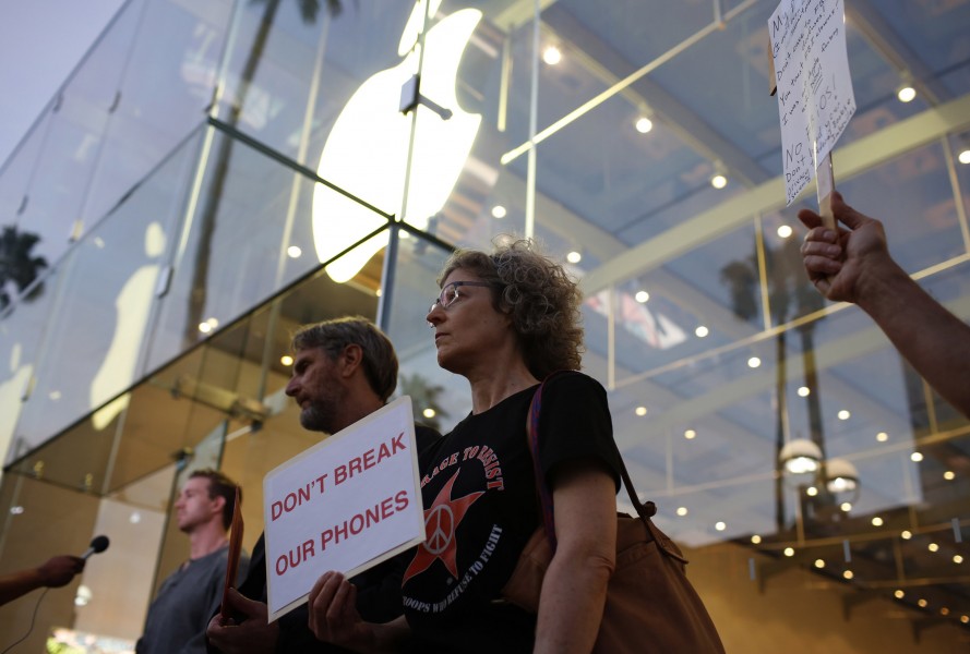 Woman stands outside apple store and carrys protesting sign