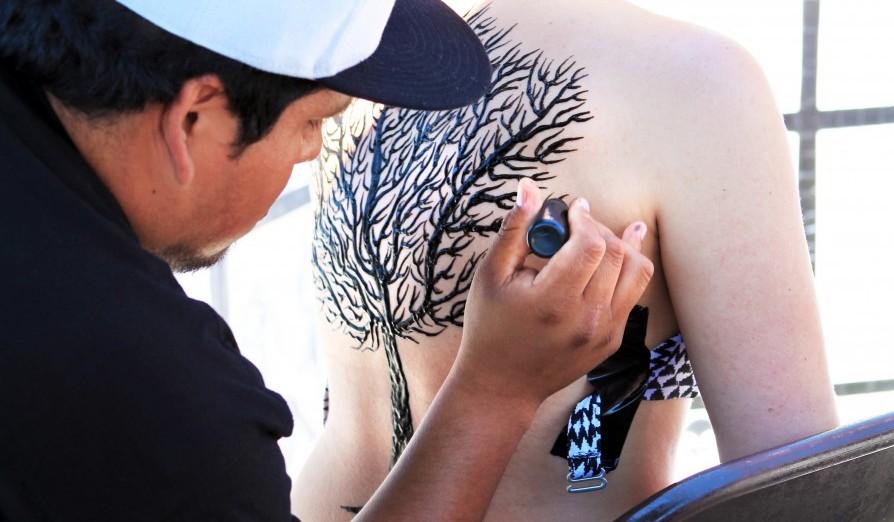 Artist draws tree on girls entire back