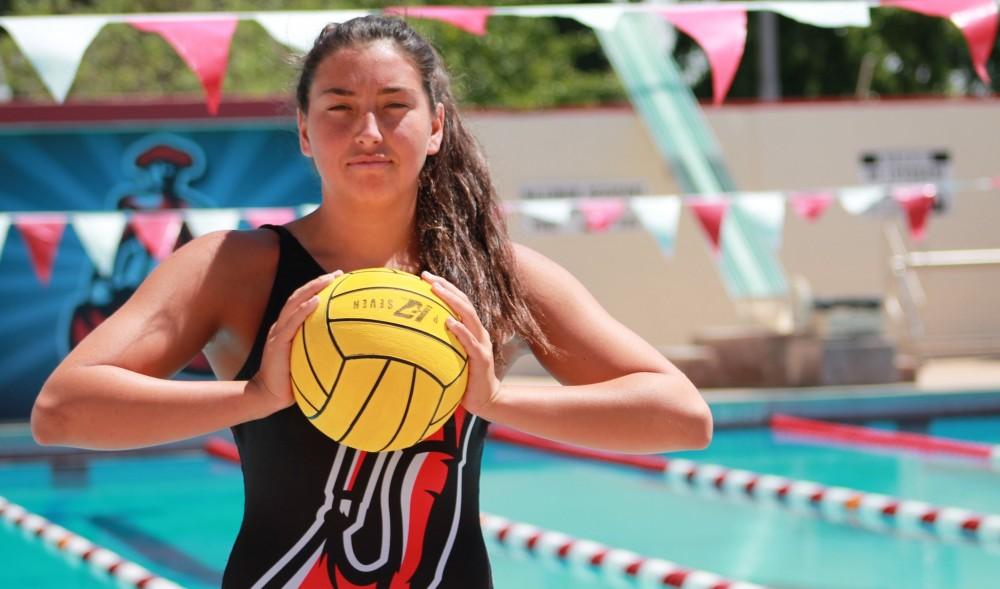 Water polo athlete poses with ball outside of pool