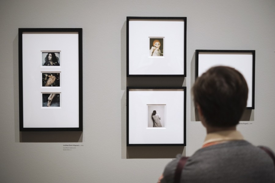 Woman stares at portraits hanging from wall