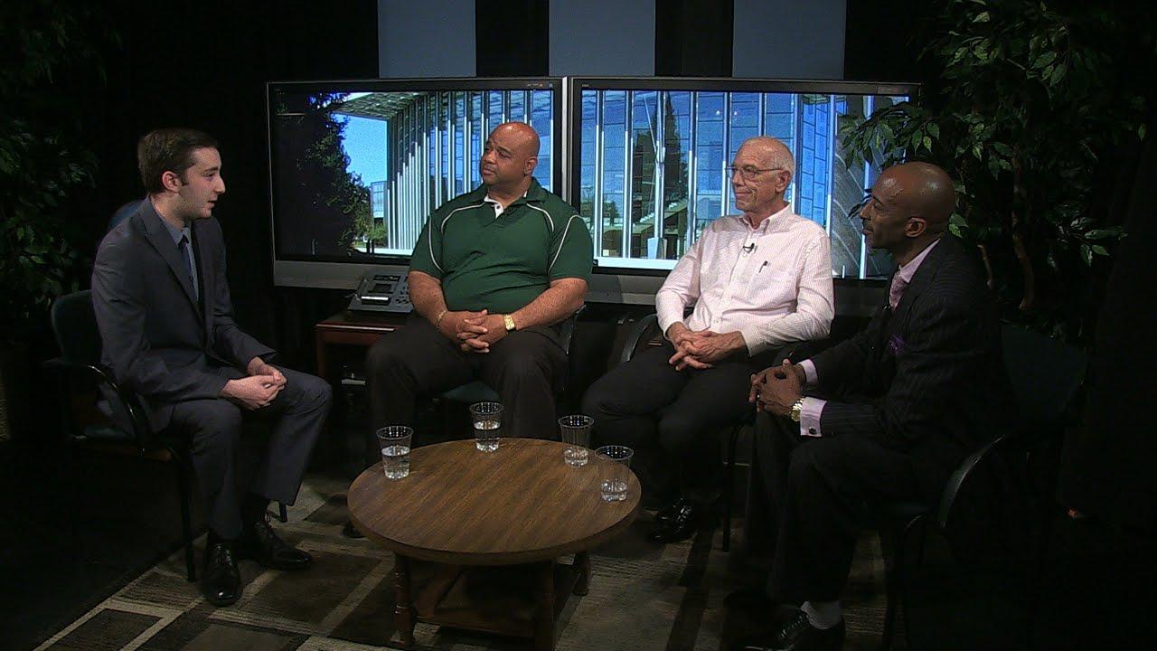 Three men sit along one another while being interviewed by another man