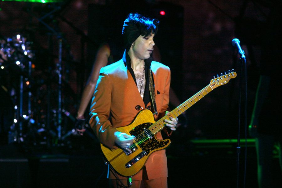 Prince stands on stage carrying a guitar