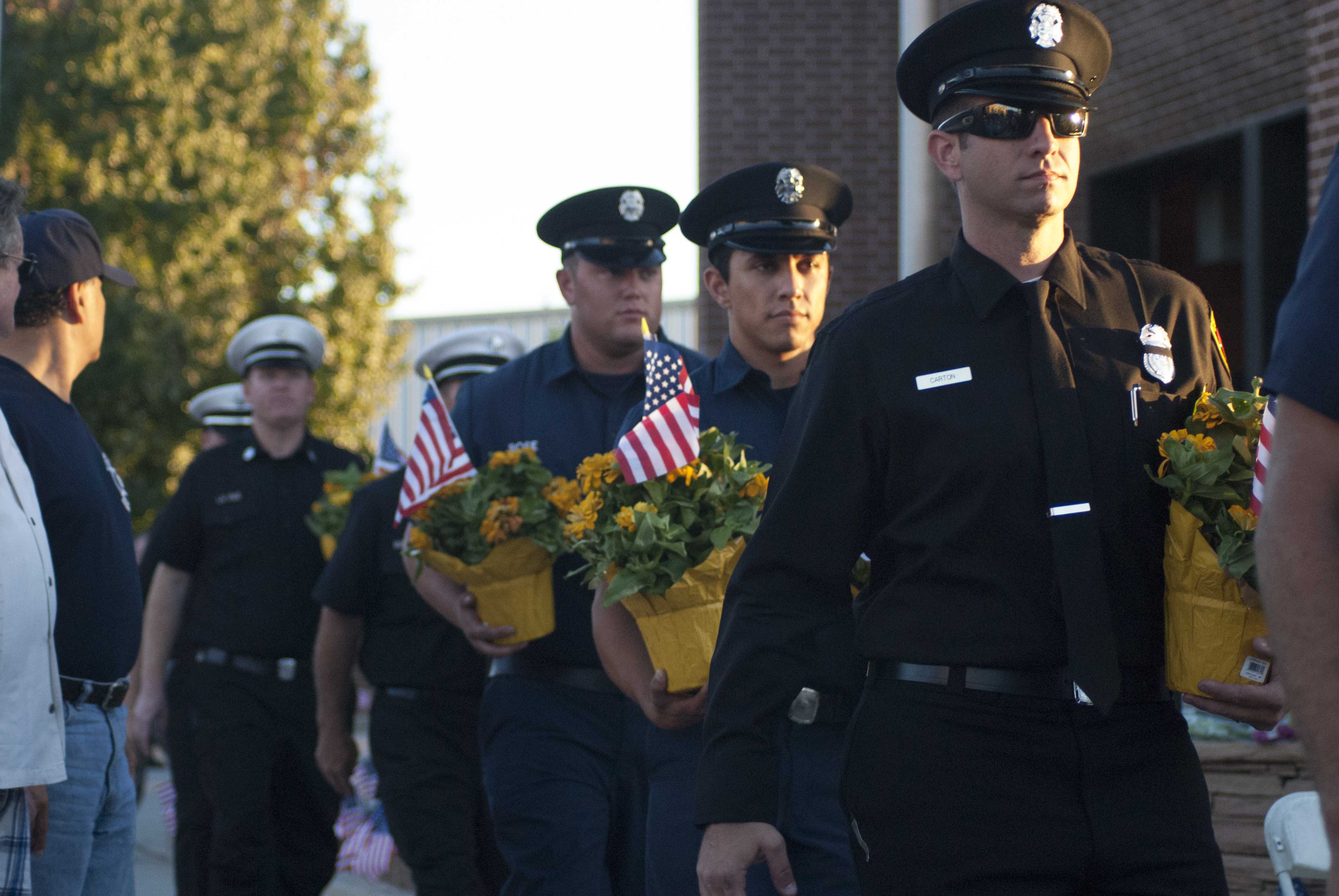 Officers carry flowers with American flags to the 9/11 Memorial Fountain at Fire Station 88 on Sept. 11, 2016. Photo credit: Nicole Wong