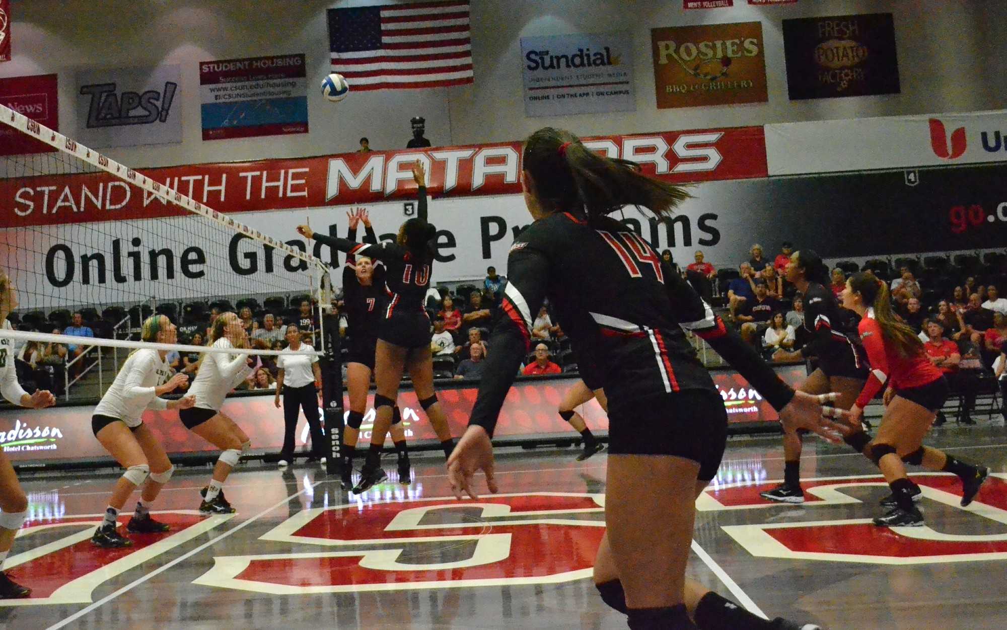 The Matadors' junior setter, Lauren Conati (center-left), and freshman middle blocker Morgan Salone (center-right) leap to intercept the volleyball during their game against the Cal Poly Mustangs on Saturday, October 1 at the Matadome. Photo credit: Eric Licas