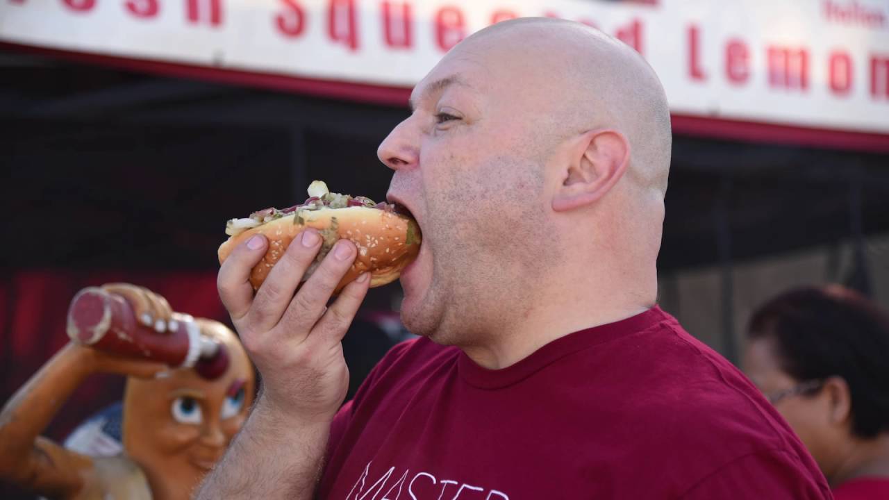 Man shown taking first bite of his hotdog