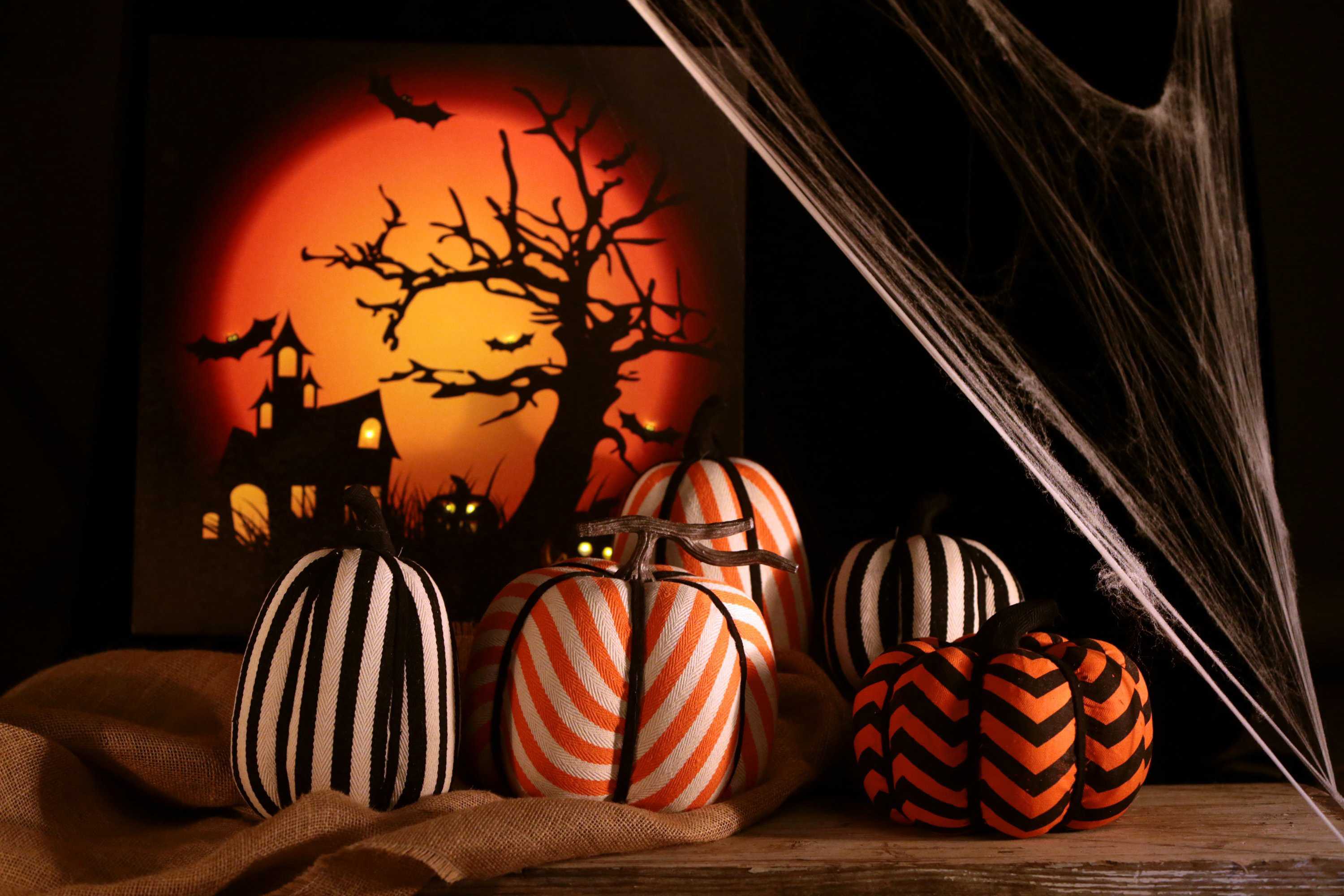 Halloween backdrop hangs behind cloth-decorated pumpkins