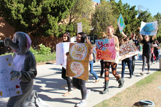 People march alongside the CSUN bookstore carrying signs with positive messges