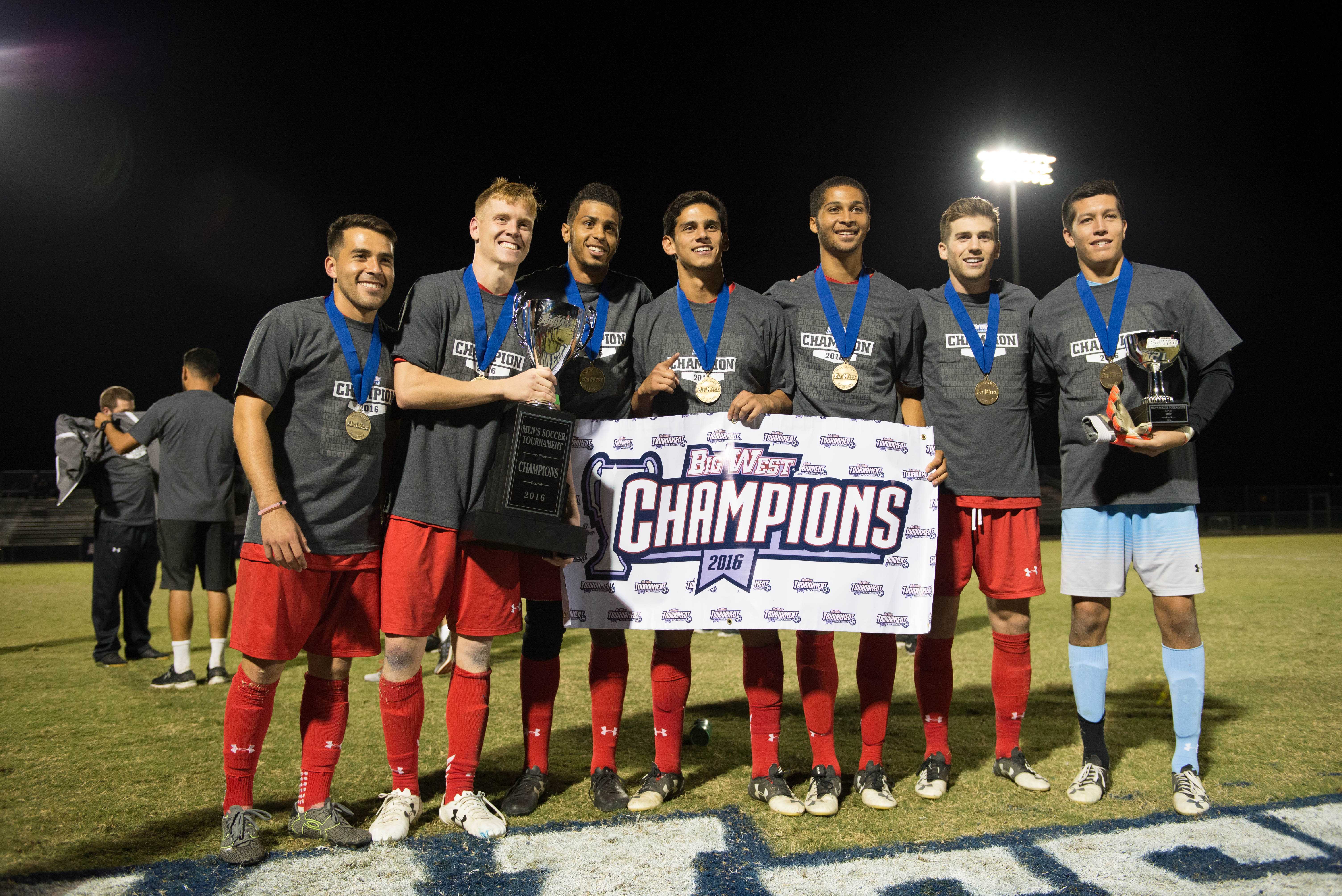 Seven men are posing with medals, trophies, and a sign which says, Big West Champions
