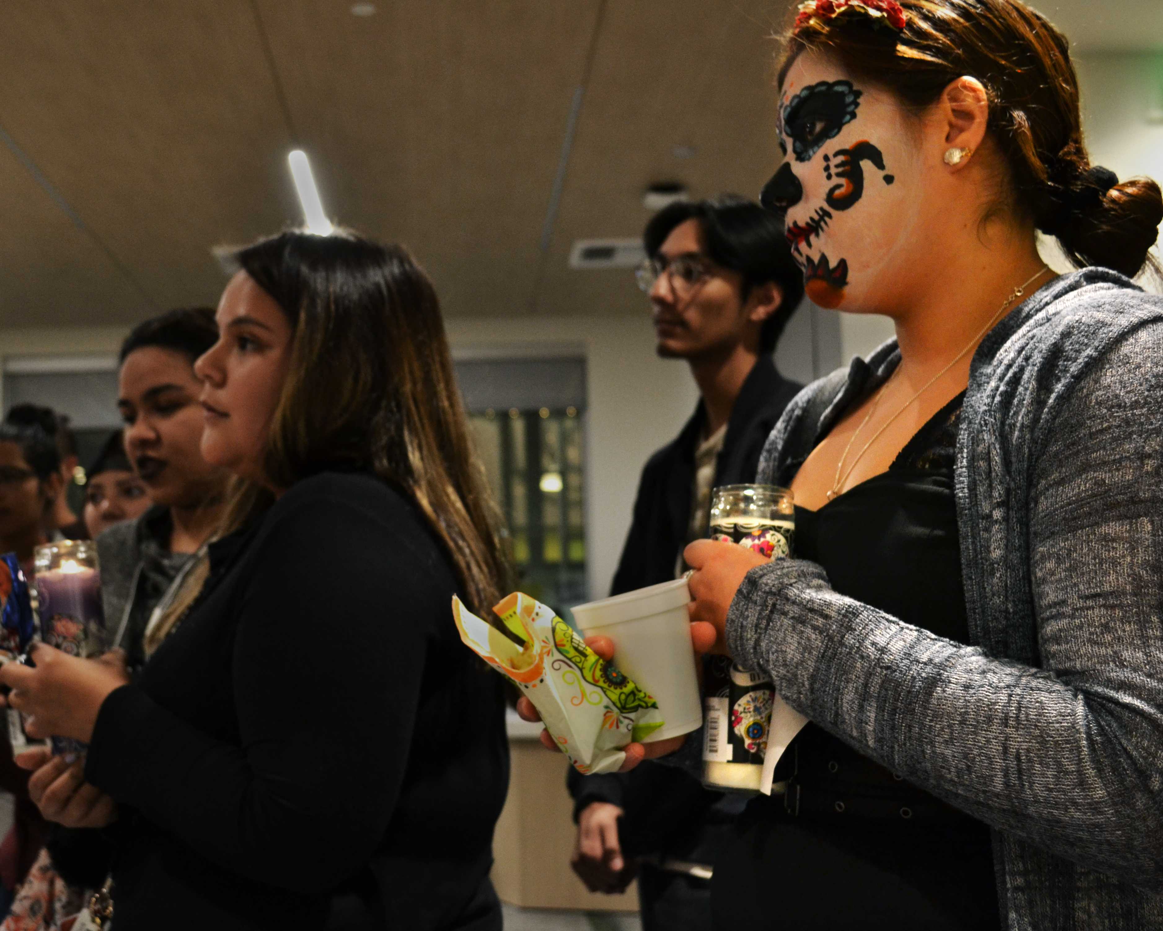 Melissa Arambula (right) looks on as CSUN students pay tribute to the dead in Honor of Dia de Los Muertos at an altar set up by the student group, Latinas Rising, on Wednesday, November  in building 21.

(Eric Licas / The Sundial)