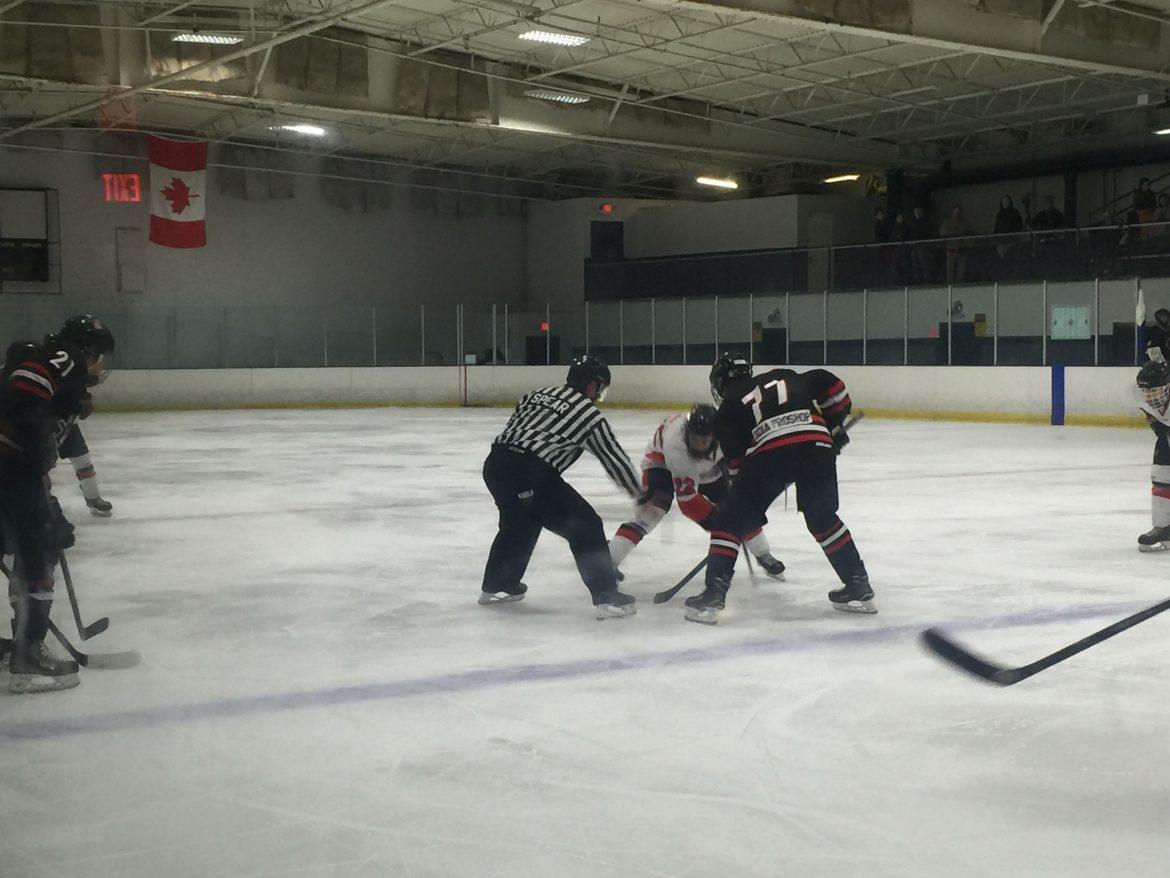 CSUN player and opposing team member wait for the referee to drop the puck