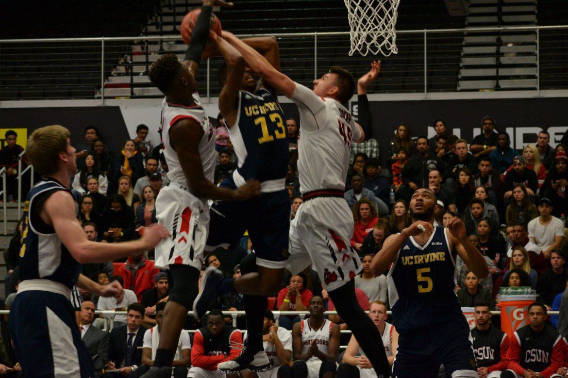 UC irvine player takes a shot at the basket and is blocked by two CSUN players