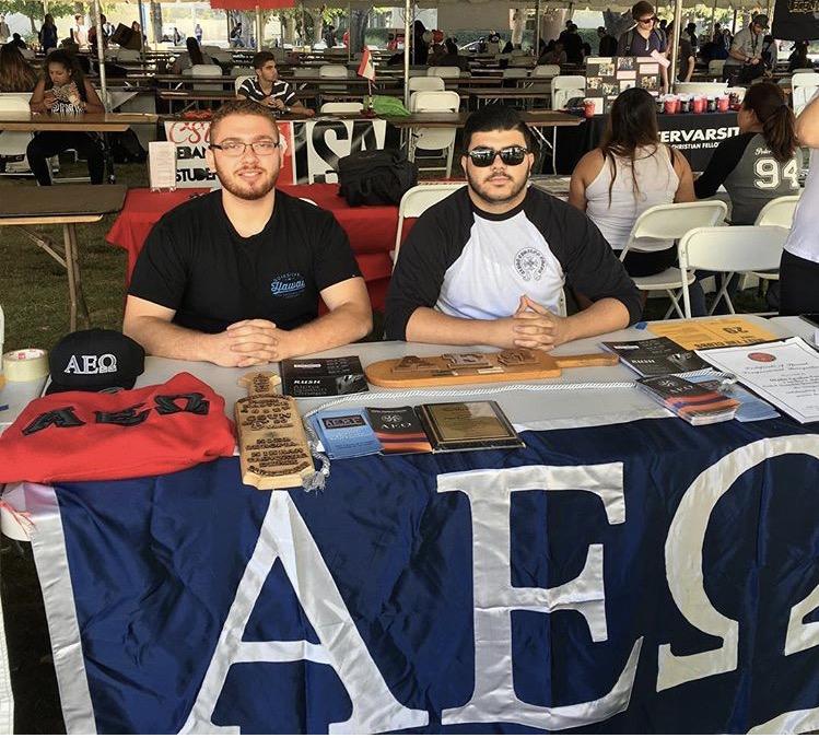Two men pictured at the Alpha Epsilon Omega table at Meet the Clubs