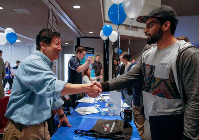 Christopher Whang shakes hands with a student at tech fest