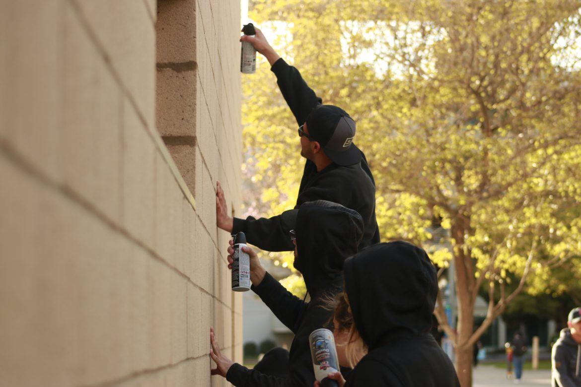 Students used cans of compressed air to clean the exterior walls of The Sundial