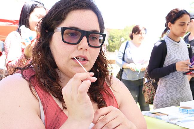 Chandra O'Connor, a 22-year-old anthropology major, gives a saliva sample to determine if she is a potential donor for a bone marrow transplant at Oviatt Park during the Be the Heroes bone marrow drive on Wednesday. Photo credit: Nikolas Samuels