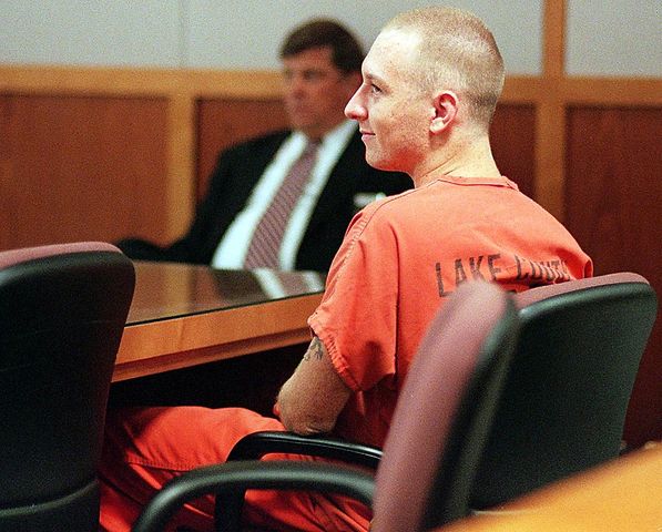 Rod Ferrell sits in court looking content wearing an orange jumsuit