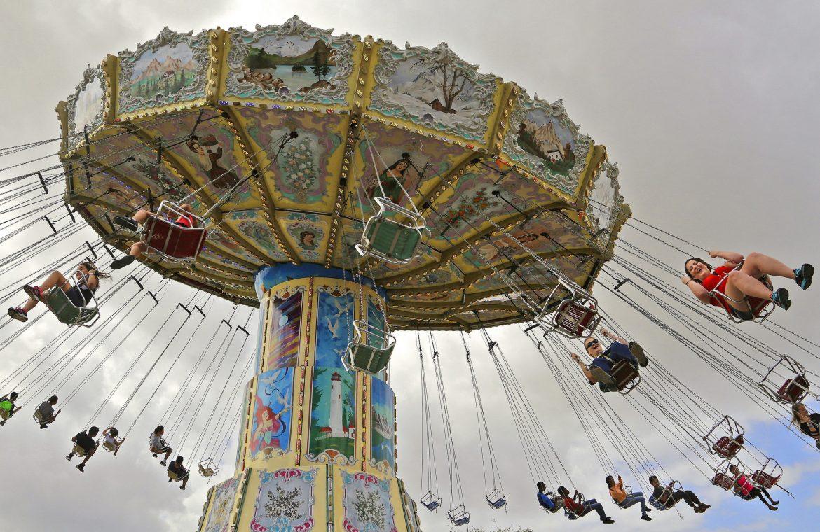 people pictured riding a large circular swing at the fair