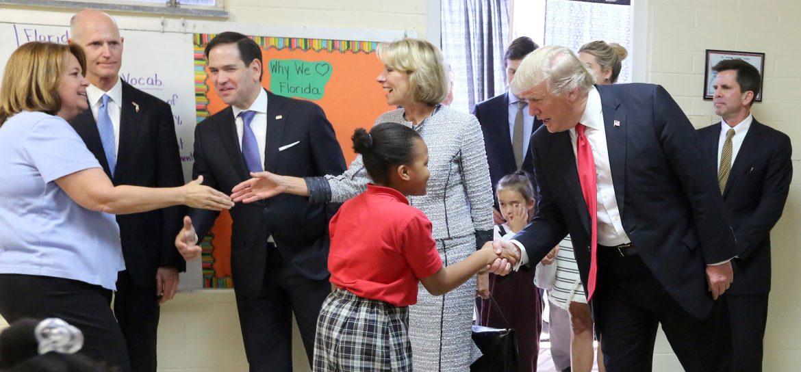 donald trump and betsey devos shakes hands with students and teachers in a classroom