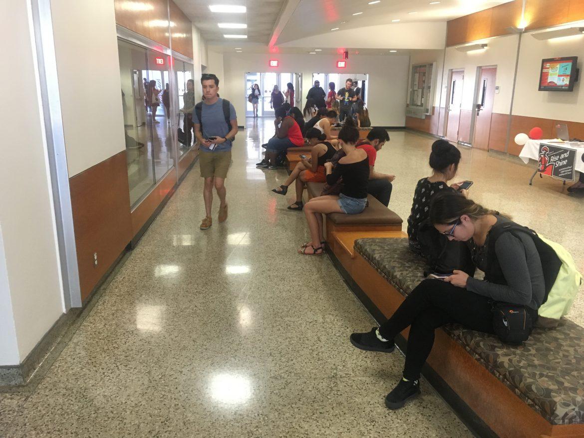 Photo shows several students sitting on the benches located on the first floor of sierra hall
