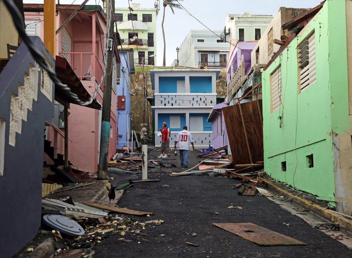 A man walks near colorful damaged buildings.  Residents of San Juan's 